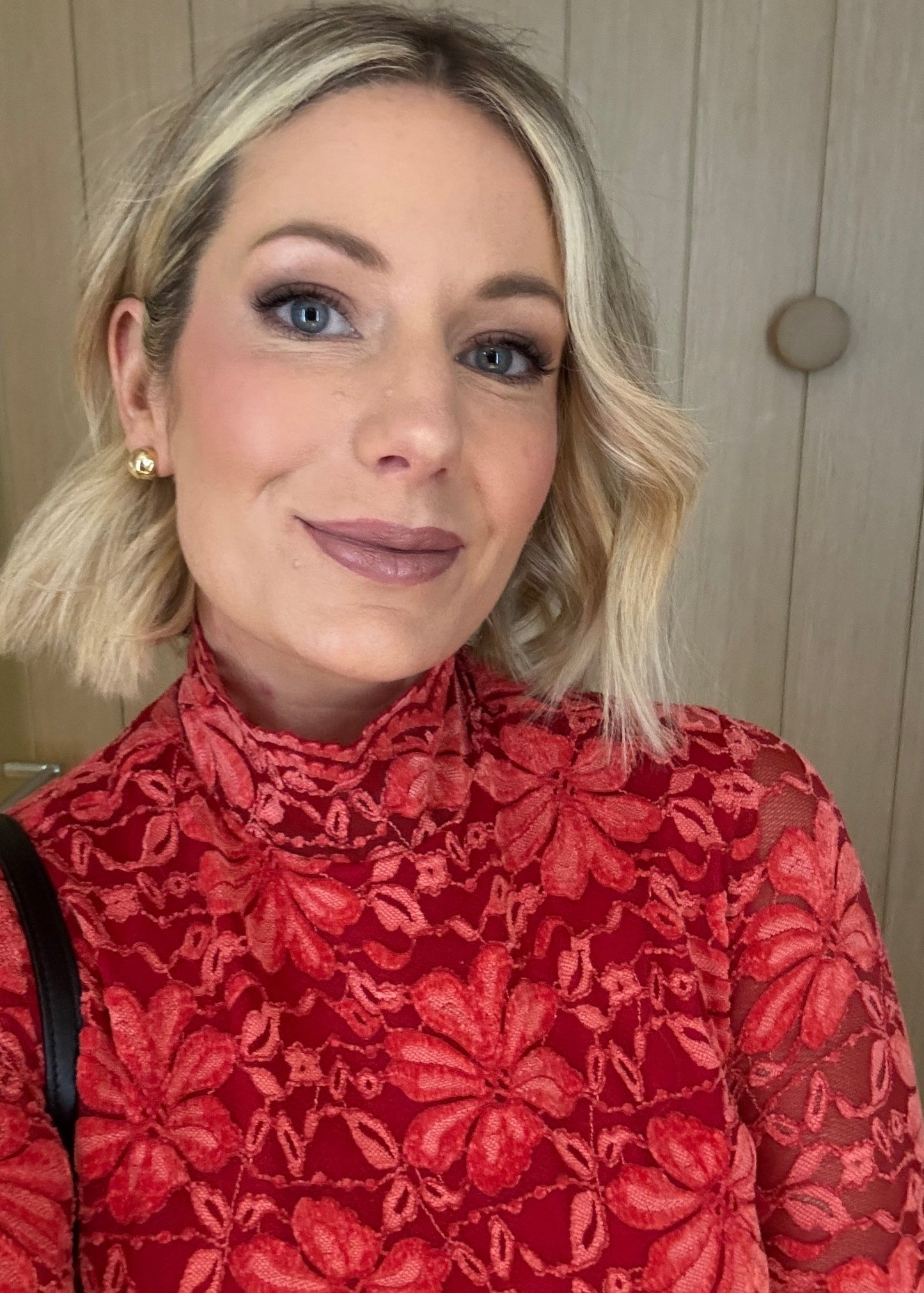Woman wearing a red floral top against a wooden background