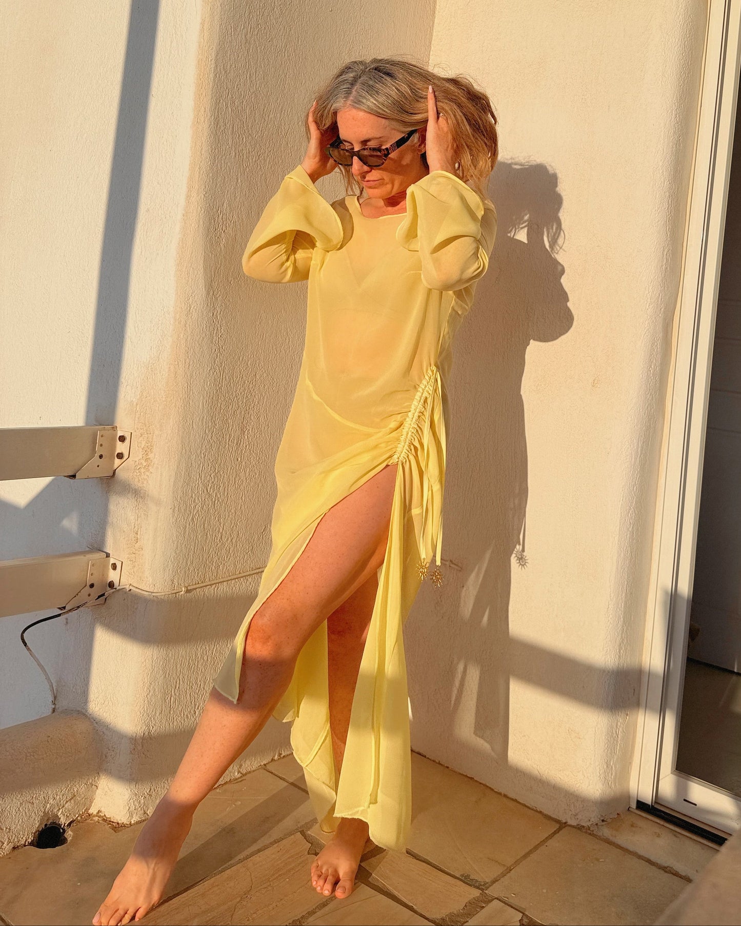 Person wearing a yellow dress standing in front of a building entrance.