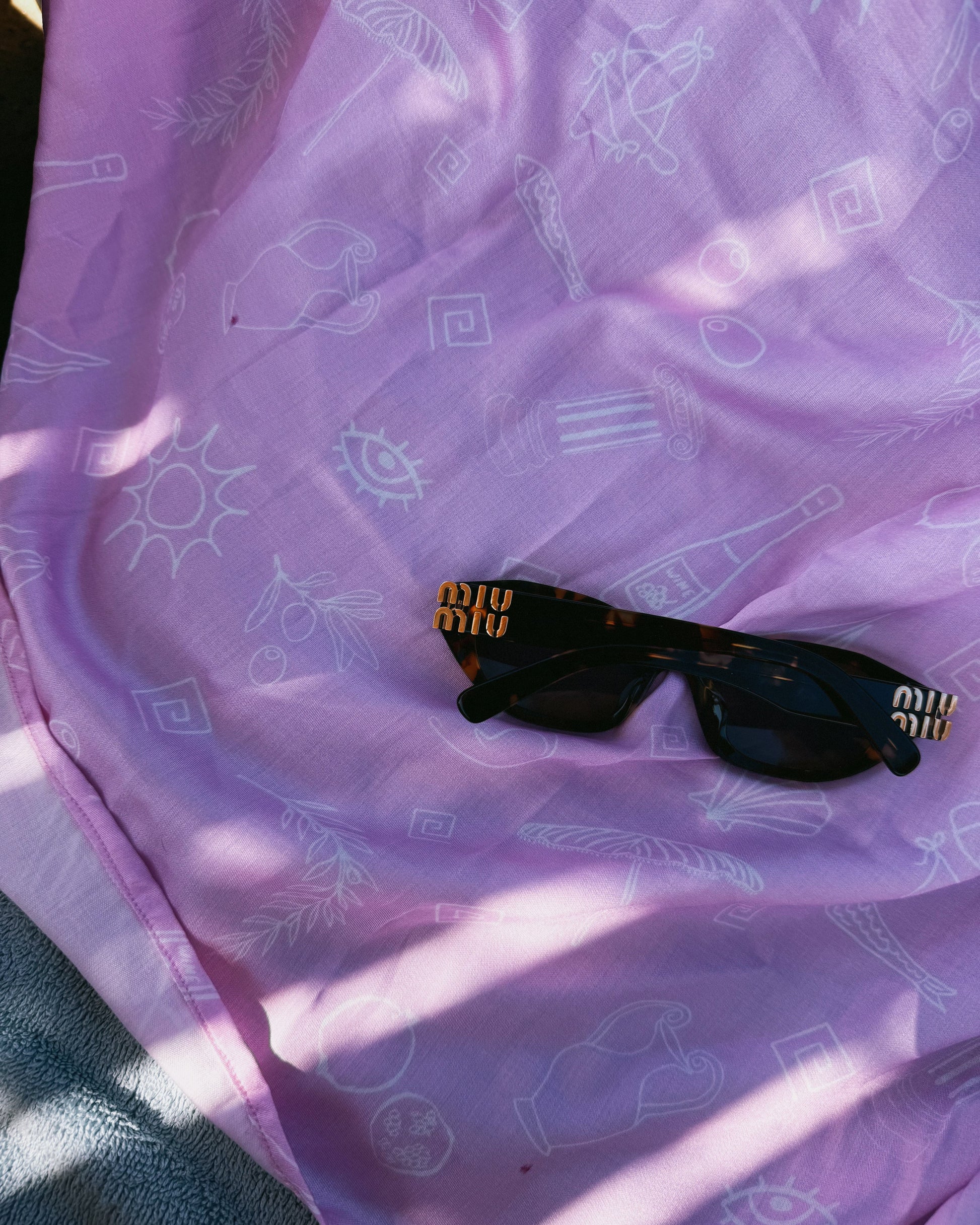 Black sunglasses on a pink fabric with white patterns