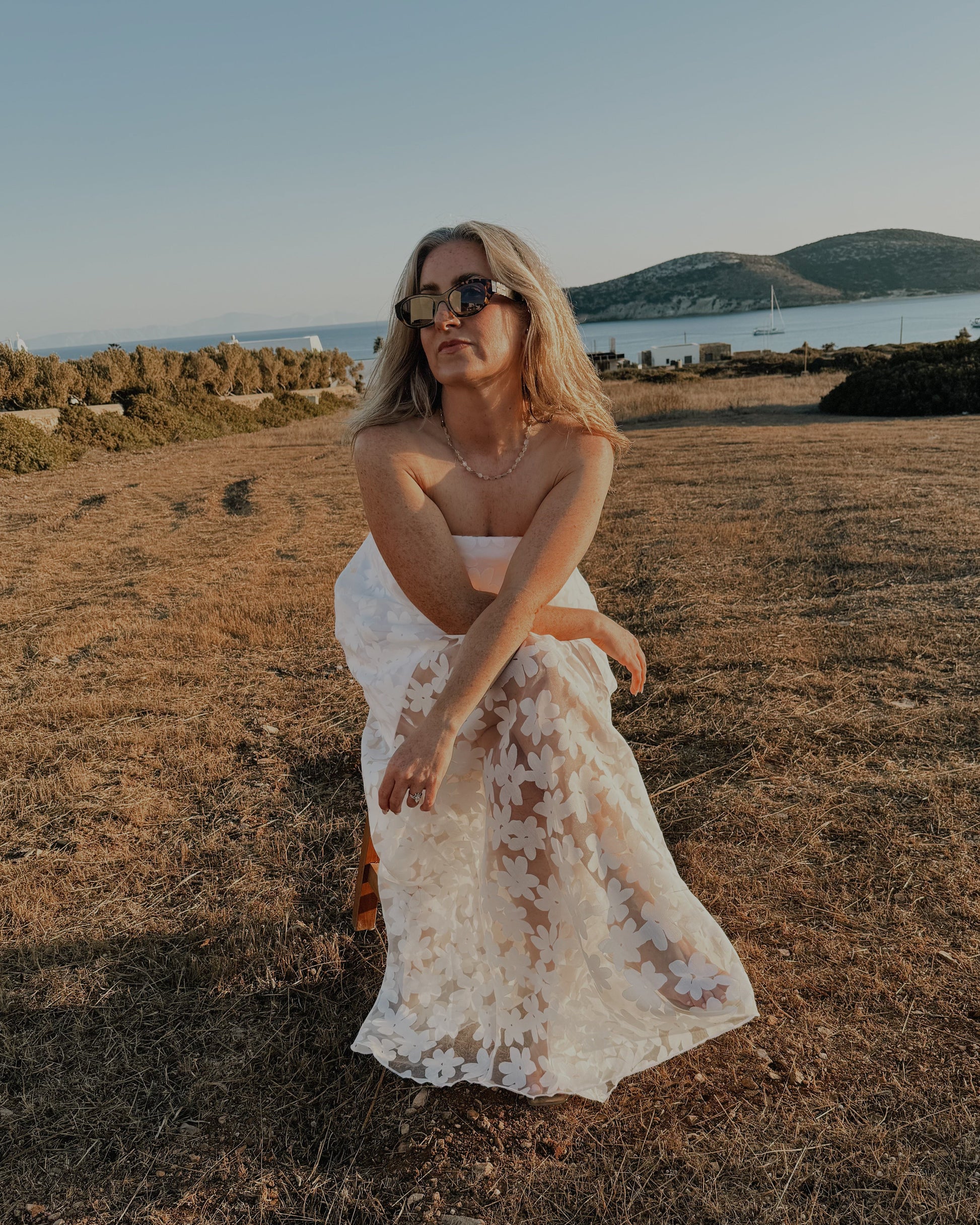 Woman in a white dress standing in a field with a scenic background