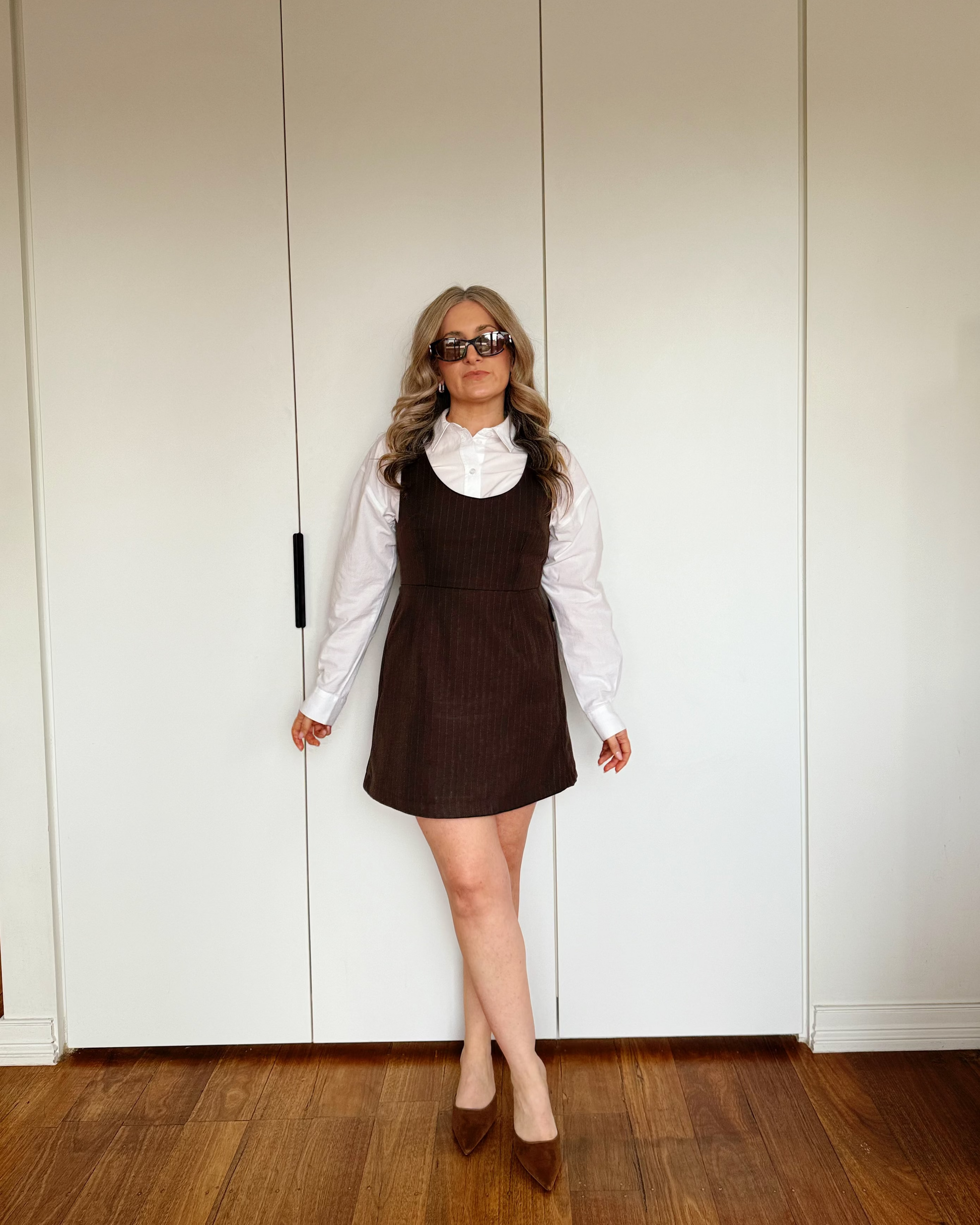 Women's structured brown pinstripe mini dress layered over a white collared shirt.