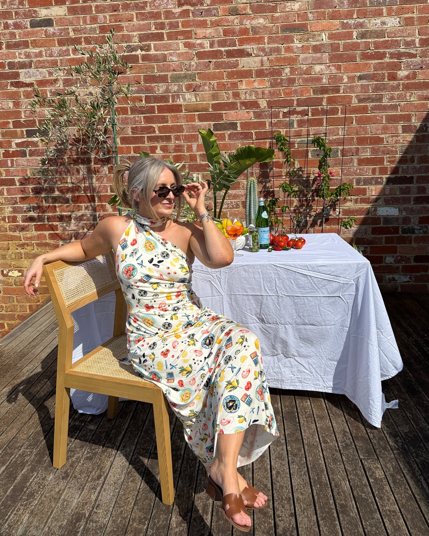 Sarinda seafood print maxi dress by By Bel styled for outdoor summer lunch with one shoulder neckline and long tie detail.