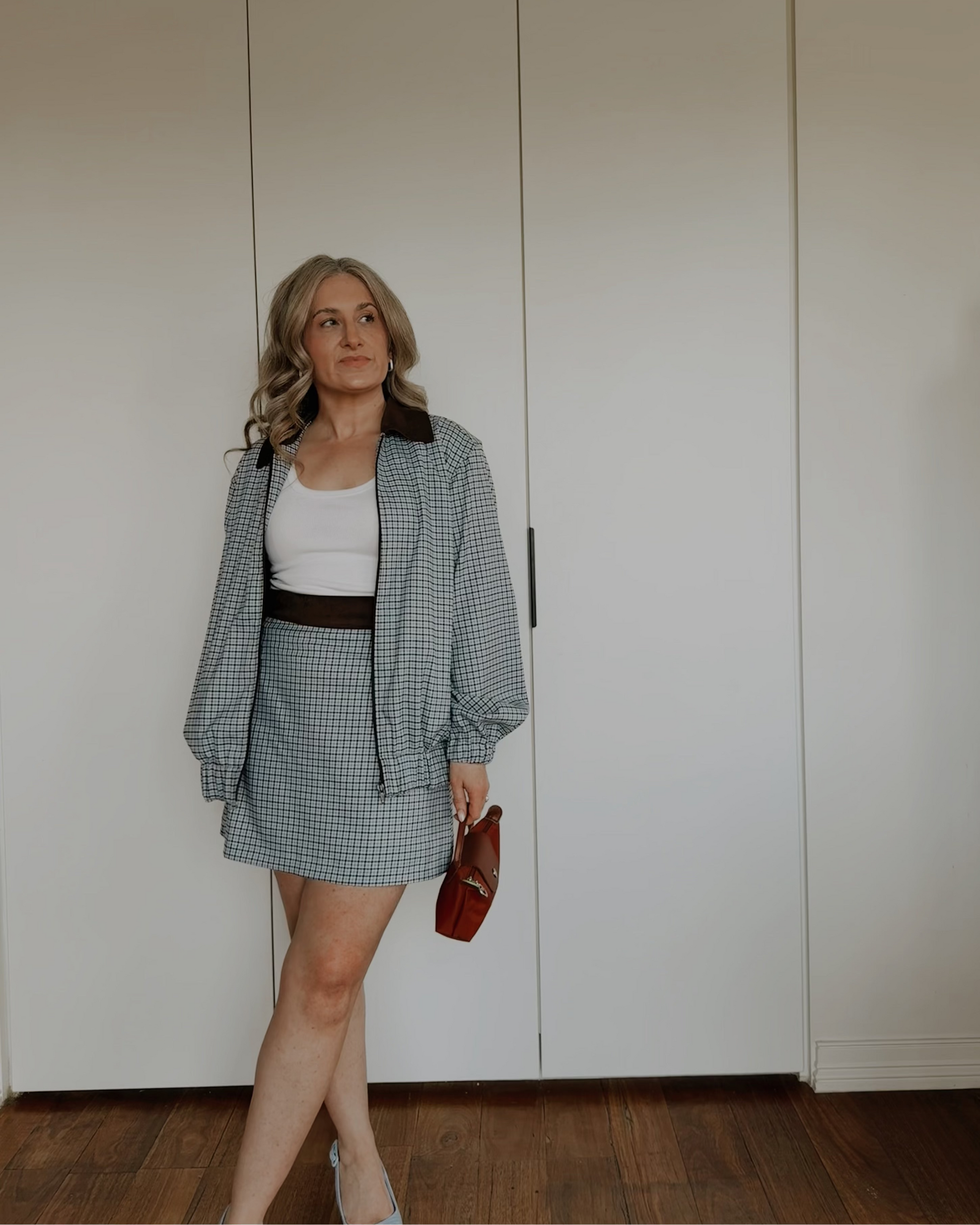 Model wearing The Tailored Mini Skirt by By Bel in a powder blue heritage check with a contrast faux suede waistband.
