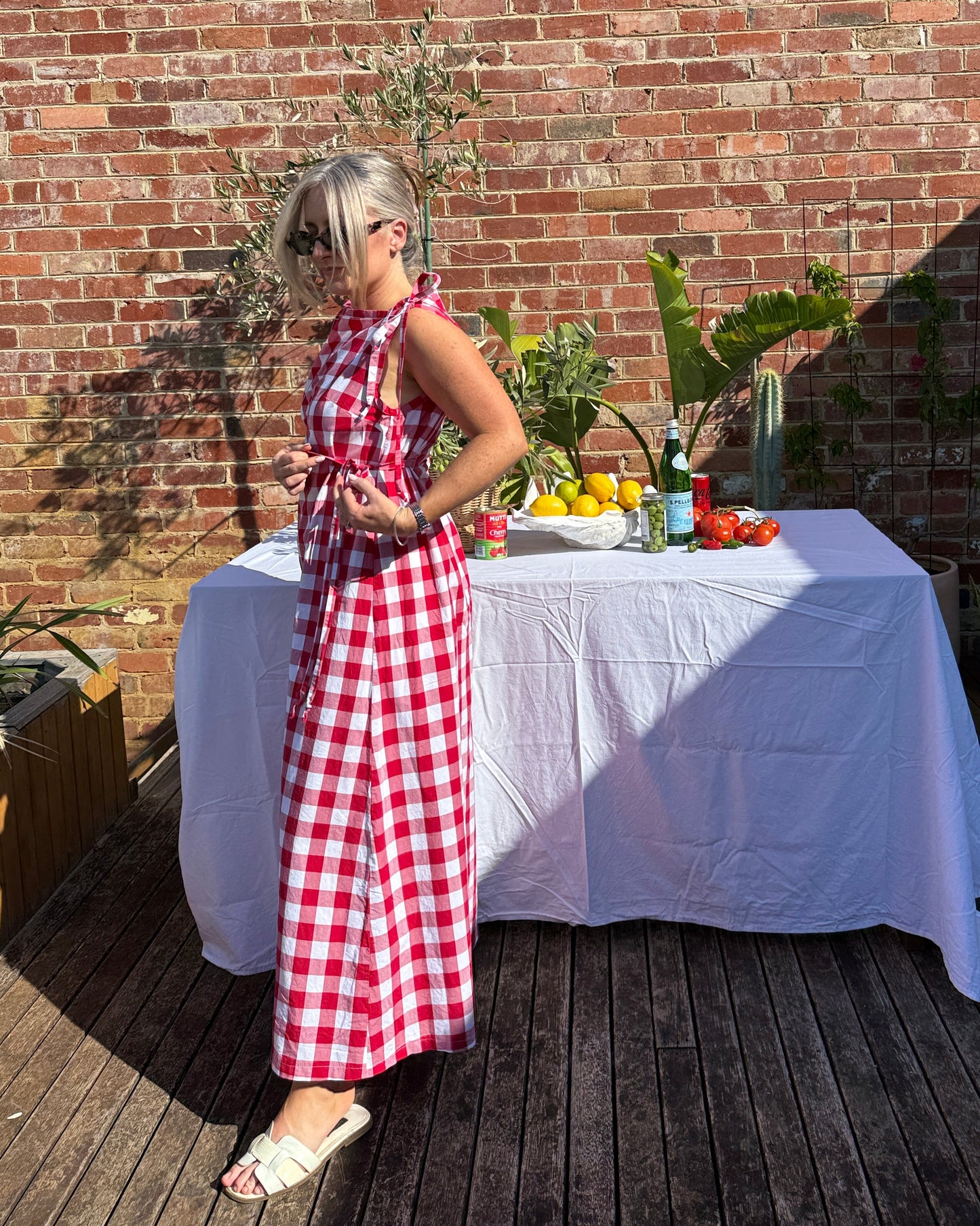 Trattoria red gingham dress with soft flowing skirt and adjustable tie details, inspired by Italian summer style.
